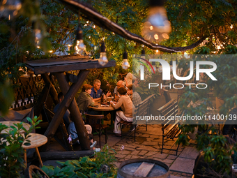 People are staying at an outdoor cafe in a courtyard in Lviv, Ukraine, on July 5, 2024. NO USE RUSSIA. NO USE BELARUS. (