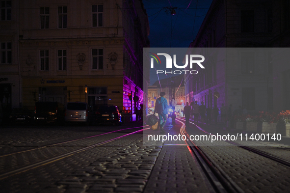 Pedestrians are crossing tram tracks in Katedralna Square at night in Lviv, Ukraine, on July 5, 2024. NO USE RUSSIA. NO USE BELARUS. 