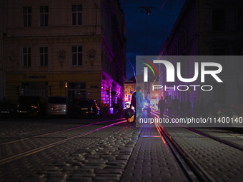 Pedestrians are crossing tram tracks in Katedralna Square at night in Lviv, Ukraine, on July 5, 2024. NO USE RUSSIA. NO USE BELARUS. (