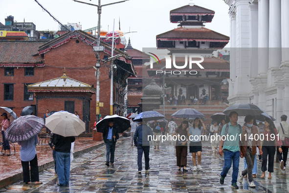 People are taking shelter under umbrellas as they walk in the rain in Kathmandu, Nepal, on July 11, 2024. Nepal is recording heavy rainfall...