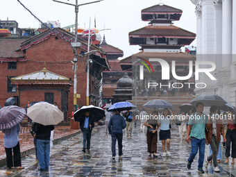 People are taking shelter under umbrellas as they walk in the rain in Kathmandu, Nepal, on July 11, 2024. Nepal is recording heavy rainfall...