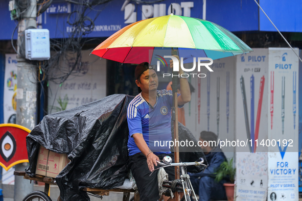 A daily wage worker is covering himself and his loads with sacks and plastic as he walks through the rain in Kathmandu, Nepal, on July 11, 2...