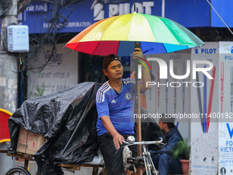 A daily wage worker is covering himself and his loads with sacks and plastic as he walks through the rain in Kathmandu, Nepal, on July 11, 2...