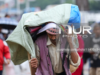 A daily wage worker is covering himself and his loads with sacks and plastic as he walks through the rain in Kathmandu, Nepal, on July 11, 2...