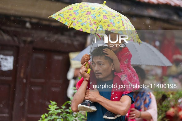 A father-daughter duo is using an umbrella to shield themselves from the rain in Kathmandu, Nepal, on July 11, 2024. Nepal is recording heav...