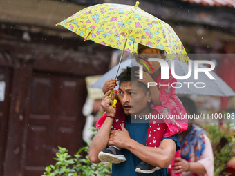 A father-daughter duo is using an umbrella to shield themselves from the rain in Kathmandu, Nepal, on July 11, 2024. Nepal is recording heav...