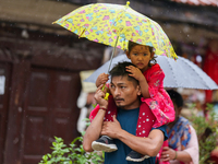 A father-daughter duo is using an umbrella to shield themselves from the rain in Kathmandu, Nepal, on July 11, 2024. Nepal is recording heav...