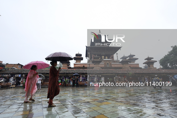 People are taking shelter under umbrellas as they walk in the rain in Kathmandu, Nepal, on July 11, 2024. Nepal is recording heavy rainfall...