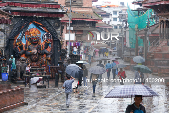 People are taking shelter under umbrellas as they walk in the rain in Kathmandu, Nepal, on July 11, 2024. Nepal is recording heavy rainfall...