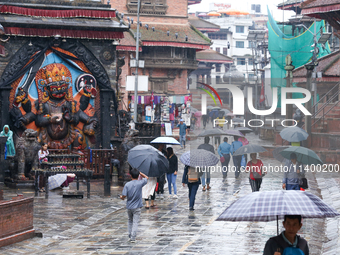 People are taking shelter under umbrellas as they walk in the rain in Kathmandu, Nepal, on July 11, 2024. Nepal is recording heavy rainfall...