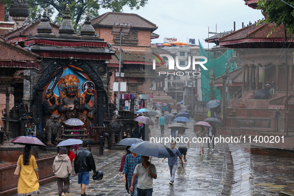 People are taking shelter under umbrellas as they walk in the rain in Kathmandu, Nepal, on July 11, 2024. Nepal is recording heavy rainfall...