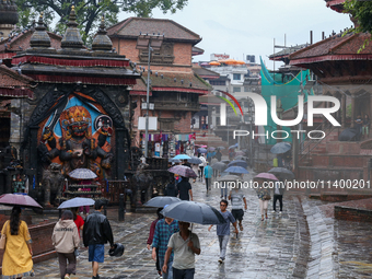 People are taking shelter under umbrellas as they walk in the rain in Kathmandu, Nepal, on July 11, 2024. Nepal is recording heavy rainfall...