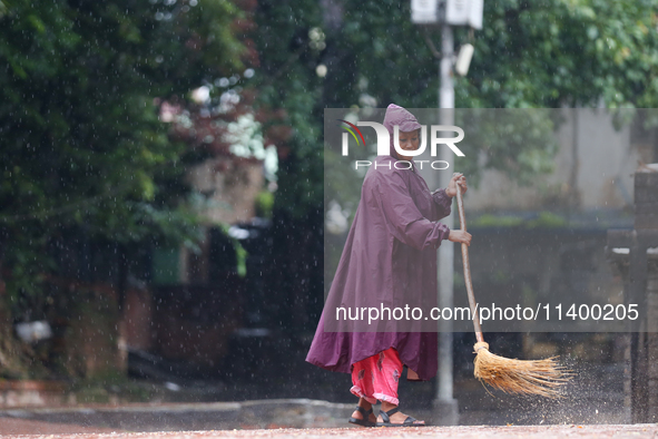 A sanitation worker is donning a raincoat and sweeping the courtyard of Basantapur Durbar Square, a UNESCO World Heritage Site, in Kathmandu...