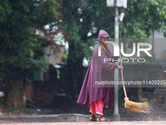 A sanitation worker is donning a raincoat and sweeping the courtyard of Basantapur Durbar Square, a UNESCO World Heritage Site, in Kathmandu...