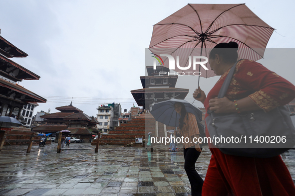 People are taking shelter under umbrellas as they walk in the rain in Kathmandu, Nepal, on July 11, 2024. Nepal is recording heavy rainfall...