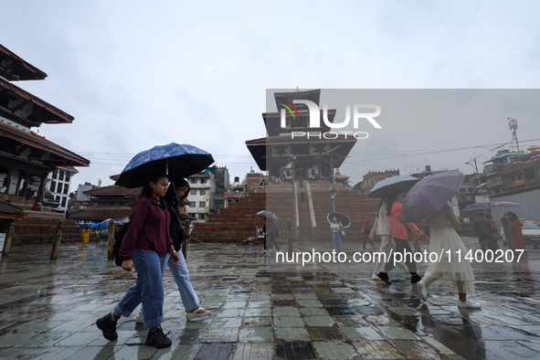 People are taking shelter under umbrellas as they walk in the rain in Kathmandu, Nepal, on July 11, 2024. Nepal is recording heavy rainfall...