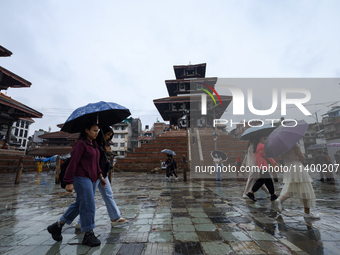 People are taking shelter under umbrellas as they walk in the rain in Kathmandu, Nepal, on July 11, 2024. Nepal is recording heavy rainfall...