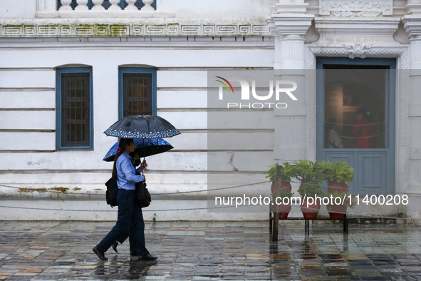 People are taking shelter under umbrellas as they walk in the rain in Kathmandu, Nepal, on July 11, 2024. Nepal is recording heavy rainfall...