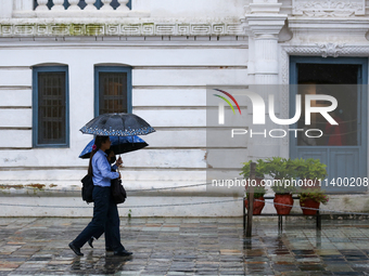 People are taking shelter under umbrellas as they walk in the rain in Kathmandu, Nepal, on July 11, 2024. Nepal is recording heavy rainfall...