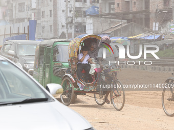 A boy is riding on a rickshaw on a dusty road in Dhaka, Bangladesh, on July 11, 2024, after returning from school. (