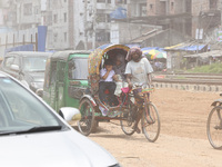 A boy is riding on a rickshaw on a dusty road in Dhaka, Bangladesh, on July 11, 2024, after returning from school. (