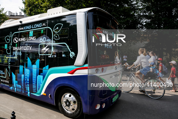 People pass as PEV6 King Long mini bus is presented for public by Barbican in Krakow, Poland on July 11, 2024. PEV6 will be included in Krak...