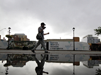 A pedestrian is walking downtown reflected in a puddle of water in Brampton, Ontario, on July 11, 2024. Remnants of Hurricane Beryl are pass...