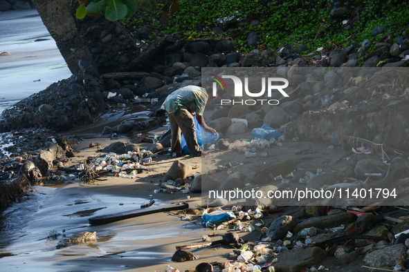 A scavenger is collecting plastic bottle waste at Padang Beach in Padang City, West Sumatra, Indonesia, on July 11, 2024. The lack of awaren...