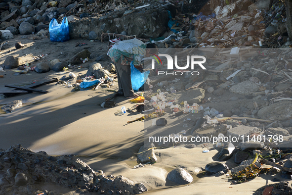 A scavenger is collecting plastic bottle waste at Padang Beach in Padang City, West Sumatra, Indonesia, on July 11, 2024. The lack of awaren...