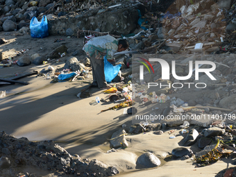 A scavenger is collecting plastic bottle waste at Padang Beach in Padang City, West Sumatra, Indonesia, on July 11, 2024. The lack of awaren...