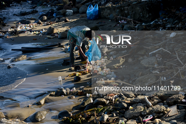 A scavenger is collecting plastic bottle waste at Padang Beach in Padang City, West Sumatra, Indonesia, on July 11, 2024. The lack of awaren...