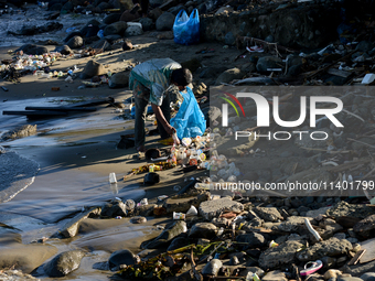 A scavenger is collecting plastic bottle waste at Padang Beach in Padang City, West Sumatra, Indonesia, on July 11, 2024. The lack of awaren...