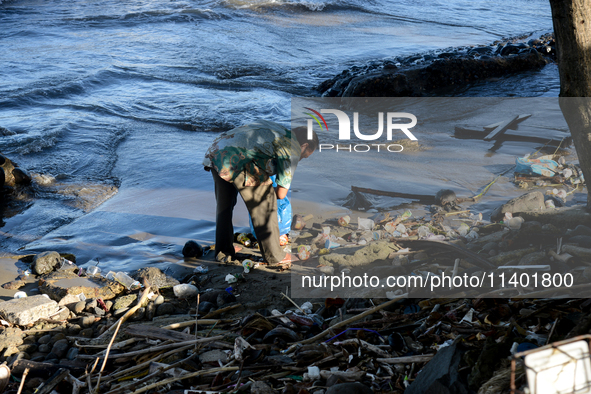 A scavenger is collecting plastic bottle waste at Padang Beach in Padang City, West Sumatra, Indonesia, on July 11, 2024. The lack of awaren...