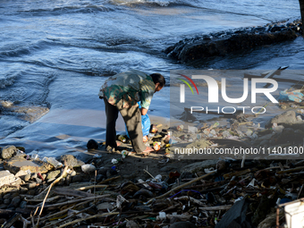 A scavenger is collecting plastic bottle waste at Padang Beach in Padang City, West Sumatra, Indonesia, on July 11, 2024. The lack of awaren...