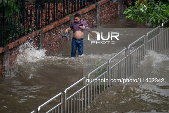 People are wading through a waterlogged street after heavy rain in Dhaka, Bangladesh, on July 12, 2024. 