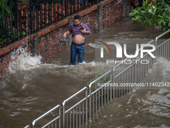 People are wading through a waterlogged street after heavy rain in Dhaka, Bangladesh, on July 12, 2024. (