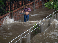 People are wading through a waterlogged street after heavy rain in Dhaka, Bangladesh, on July 12, 2024. (