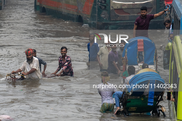 People are wading through a waterlogged street after heavy rain in Dhaka, Bangladesh, on July 12, 2024. 