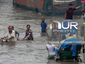 People are wading through a waterlogged street after heavy rain in Dhaka, Bangladesh, on July 12, 2024. (