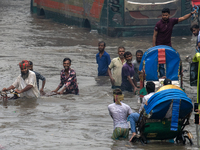 People are wading through a waterlogged street after heavy rain in Dhaka, Bangladesh, on July 12, 2024. (