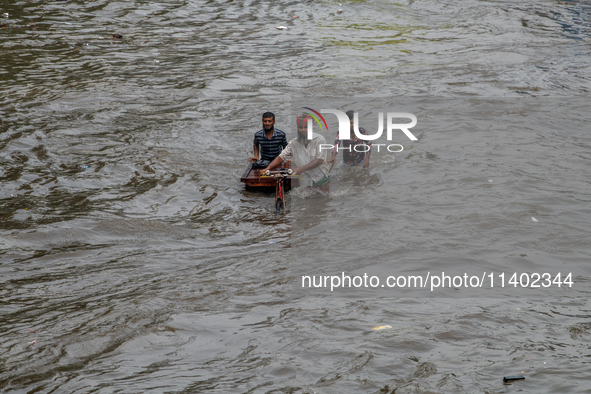 People are wading through a waterlogged street after heavy rain in Dhaka, Bangladesh, on July 12, 2024. 