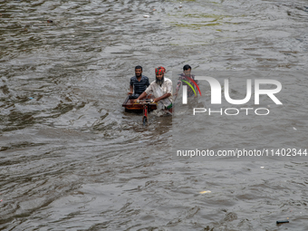 People are wading through a waterlogged street after heavy rain in Dhaka, Bangladesh, on July 12, 2024. (