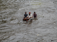 People are wading through a waterlogged street after heavy rain in Dhaka, Bangladesh, on July 12, 2024. (