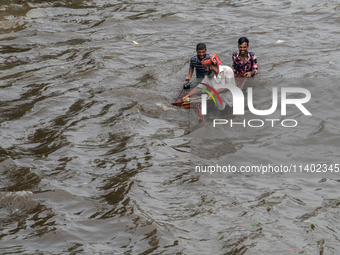 People are wading through a waterlogged street after heavy rain in Dhaka, Bangladesh, on July 12, 2024. (