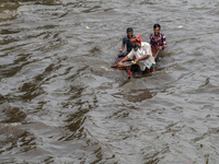 People are wading through a waterlogged street after heavy rain in Dhaka, Bangladesh, on July 12, 2024. (