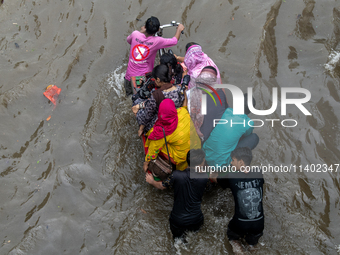 People are wading through a waterlogged street after heavy rain in Dhaka, Bangladesh, on July 12, 2024. (