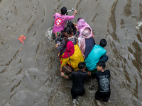 People are wading through a waterlogged street after heavy rain in Dhaka, Bangladesh, on July 12, 2024. (