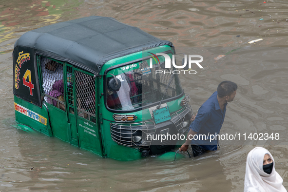 People are wading through a waterlogged street after heavy rain in Dhaka, Bangladesh, on July 12, 2024. 