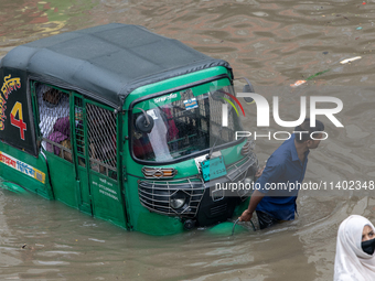 People are wading through a waterlogged street after heavy rain in Dhaka, Bangladesh, on July 12, 2024. (