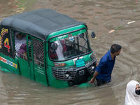 People are wading through a waterlogged street after heavy rain in Dhaka, Bangladesh, on July 12, 2024. (